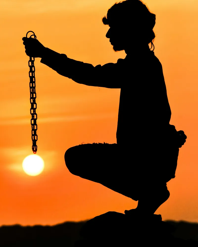 Silhouette di una persona al tramonto che tiene una catena spezzata, simbolo dell'esdebitazione